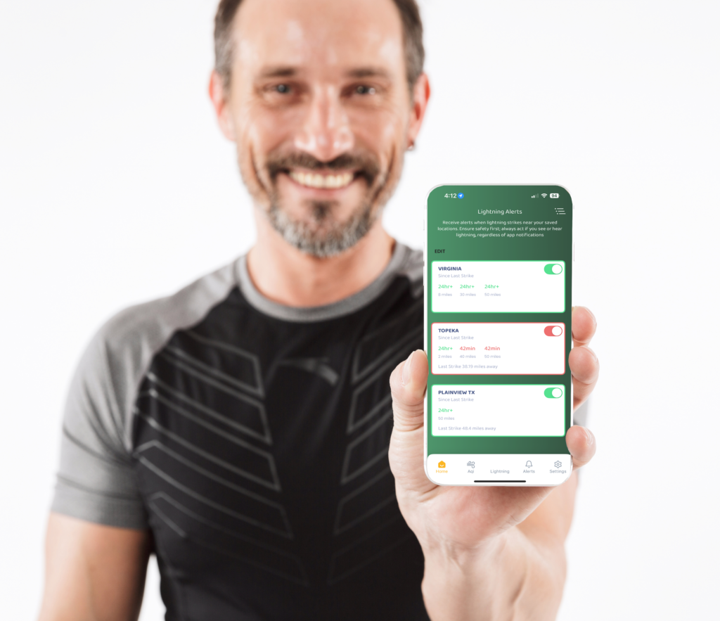 A man holding up the Zelus system app showing the lightning alert screen.